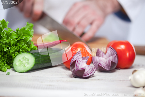 Image of Chef cutting a green lettuce his kitchen