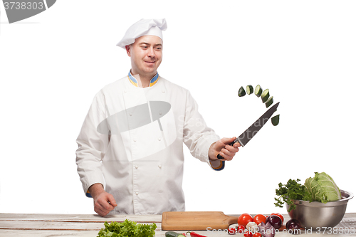 Image of Chef cutting a green cucumber in his kitchen
