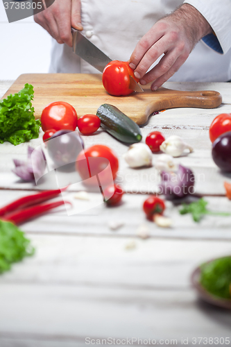 Image of Chef cutting a red tomato his kitchen