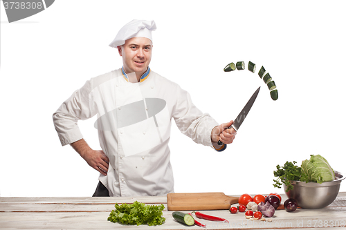 Image of Chef cutting a green cucumber in his kitchen