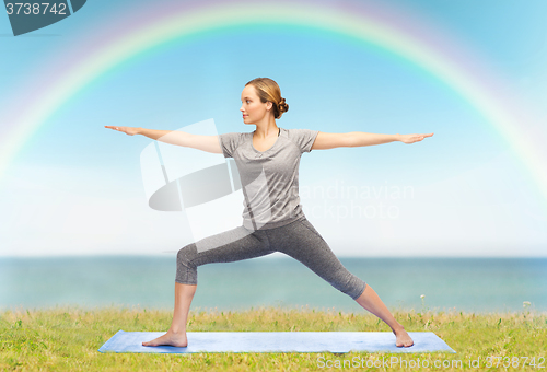 Image of woman making yoga warrior pose on mat