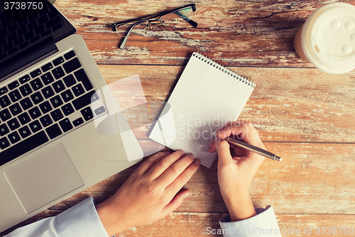 Image of close up of female hands with laptop and notebook