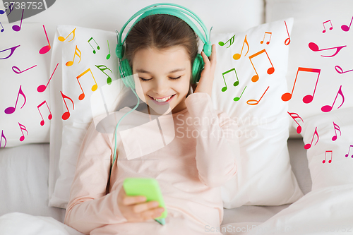 Image of happy girl lying in bed with smartphone at home