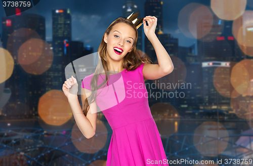 Image of happy young woman in crown over night city 