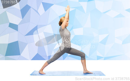 Image of woman making yoga warrior pose on mat