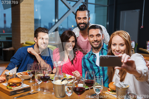 Image of friends taking selfie by smartphone at restaurant