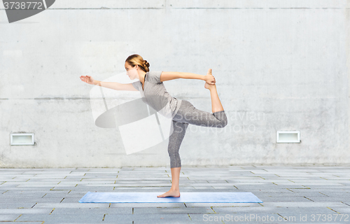 Image of woman making yoga in lord of the dance pose on mat