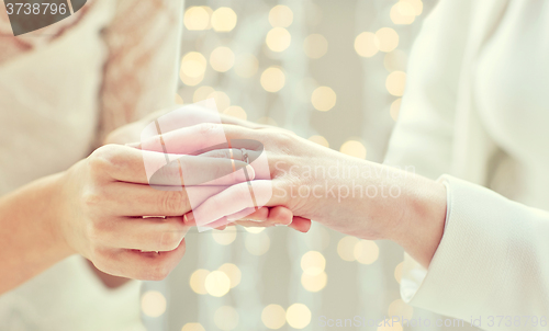 Image of close up of lesbian couple hands with wedding ring