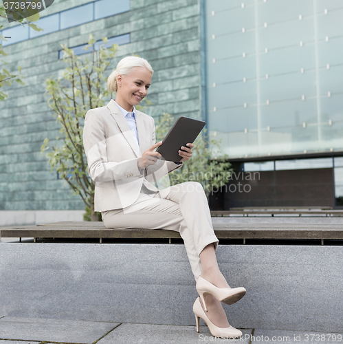 Image of smiling businesswoman with tablet pc outdoors