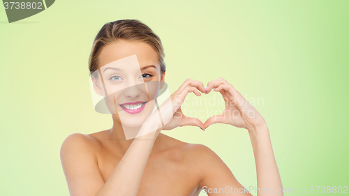 Image of smiling young woman showing heart shape hand sign