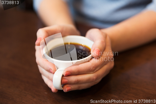 Image of close up of woman holding hot black coffee cup