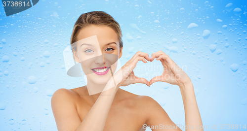 Image of smiling young woman showing heart shape hand sign