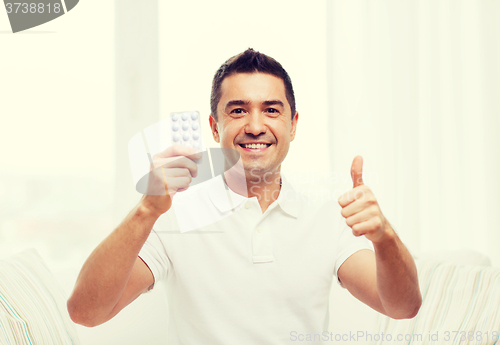 Image of happy man with pack of pills showing thumbs up