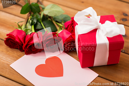 Image of close up of gift box, red roses and greeting card