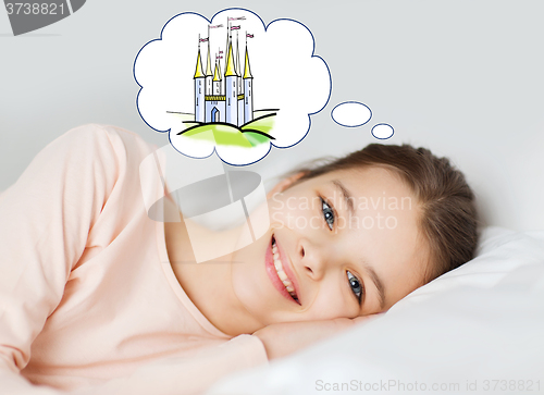 Image of smiling girl lying in bed and dreaming of castle