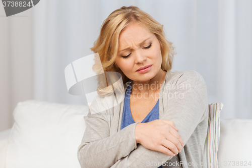 Image of unhappy woman suffering from pain in hand at home