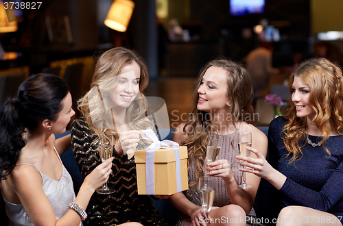 Image of happy women with champagne and gift at night club