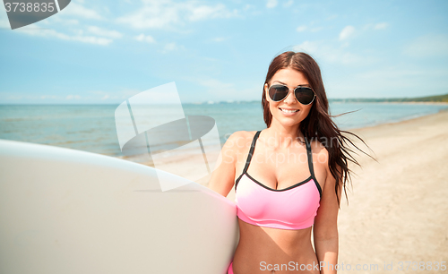 Image of smiling young woman with surfboard on beach