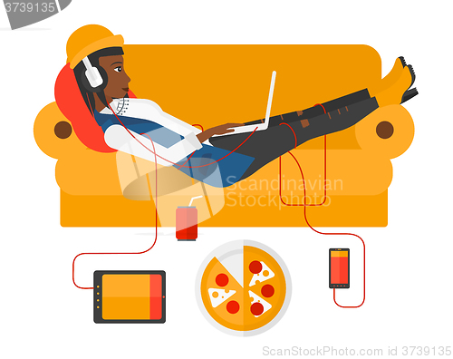 Image of Woman with gadgets lying on sofa.