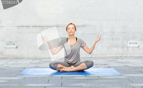 Image of woman making yoga meditation in lotus pose on mat