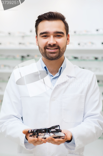 Image of man optician with glasses in coat at optics store