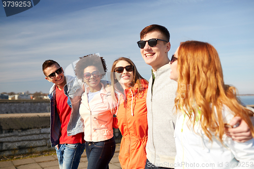 Image of happy teenage friends walking along city street