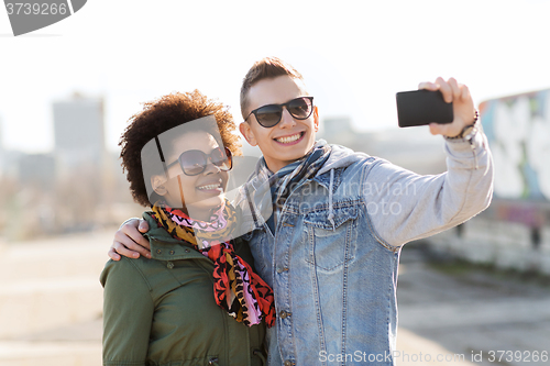 Image of happy teenage friends in shades taking selfie