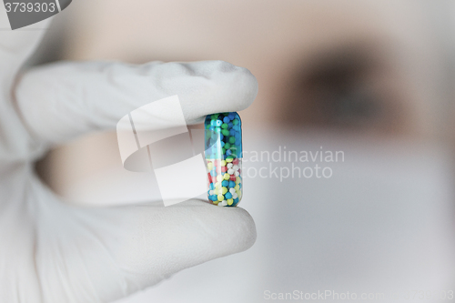 Image of close up of scientist holding pill in lab