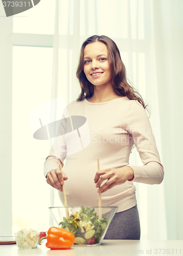 Image of happy pregnant woman preparing food at home