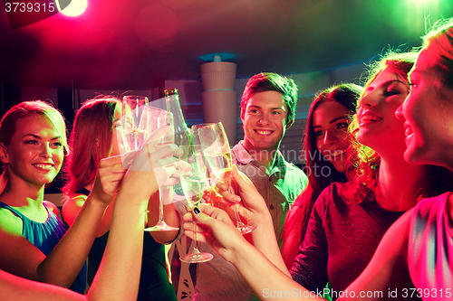 Image of smiling friends with wine glasses and beer in club