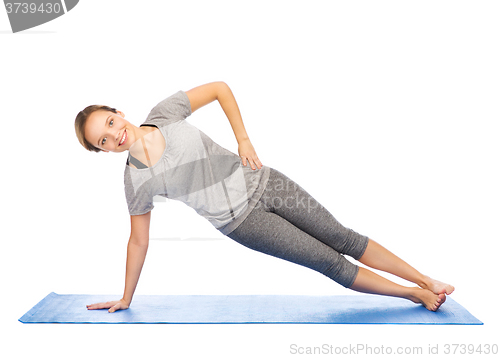 Image of woman making yoga in side plank pose on mat