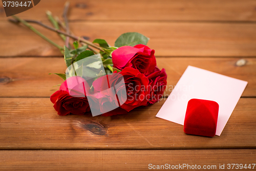 Image of close up of gift box, red roses and greeting card