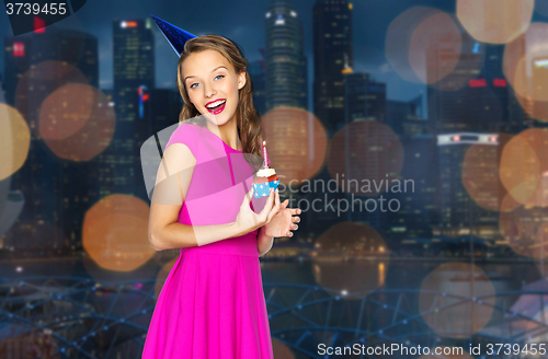 Image of happy woman with birthday cupcake over night city 