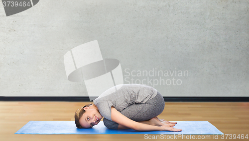 Image of happy woman making yoga in child pose on mat