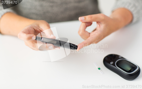 Image of close up of woman making blood test by glucometer