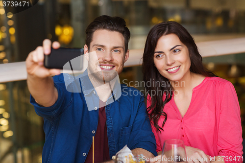 Image of couple taking selfie by smartphone at restaurant