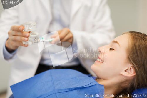 Image of happy dentist showing jaw layout to patient girl