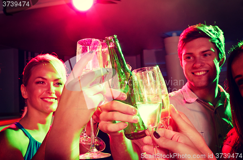 Image of smiling friends with wine glasses and beer in club