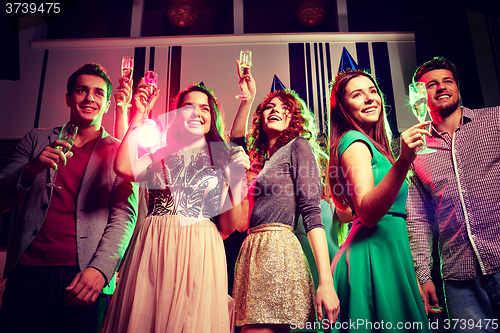 Image of smiling friends with glasses of champagne in club