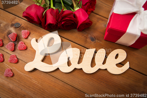 Image of close up of gift box, red roses and greeting card