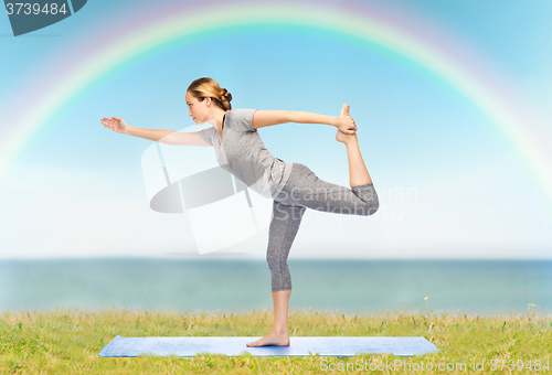 Image of woman making yoga in lord of the dance pose on mat