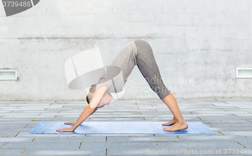 Image of woman making yoga dog pose on mat