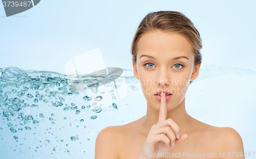 Image of beautiful young woman holding finger on lips