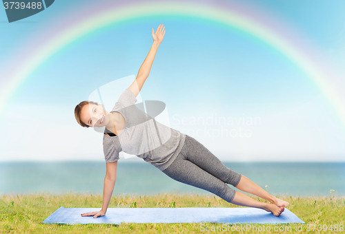 Image of woman making yoga in side plank pose on mat