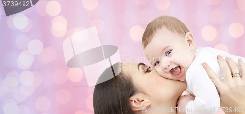 Image of happy mother kissing her baby over pink lights