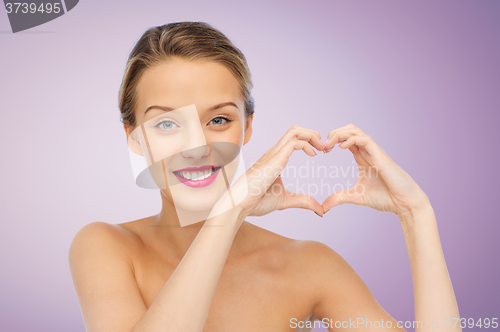 Image of smiling young woman showing heart shape hand sign