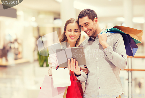 Image of couple with tablet pc and shopping bags in mall