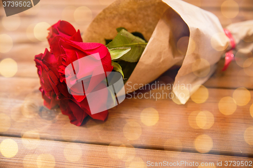 Image of close up of red roses bunch wrapped into paper