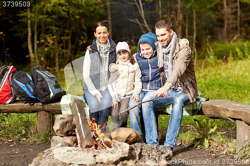 Image of happy family sitting on bench at camp fire