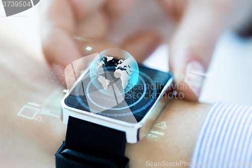 Image of close up of hand with globe hologram on smartwatch